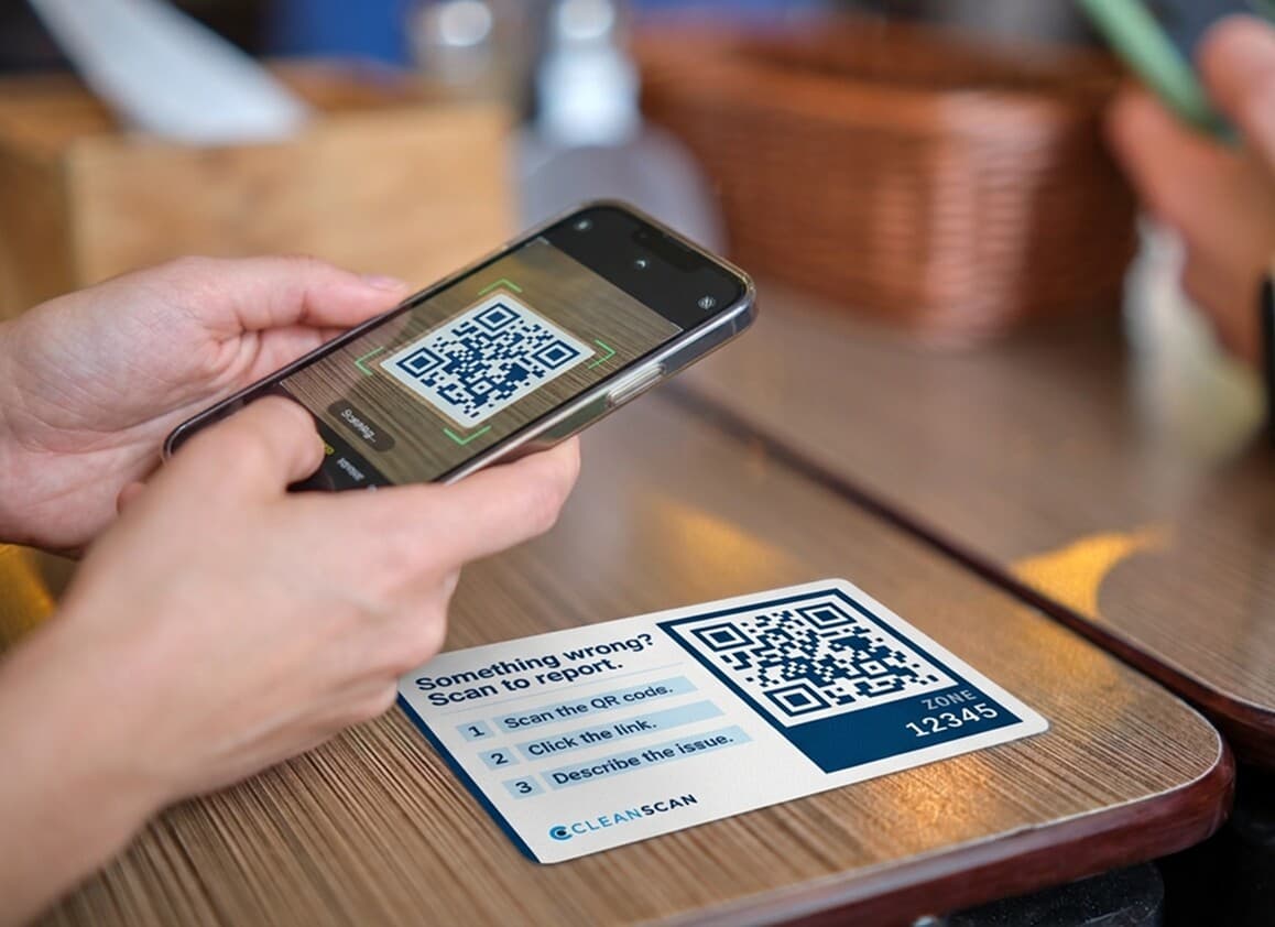 Close-up of a hand holding a smartphone near an NFC tag mounted on a facility wall